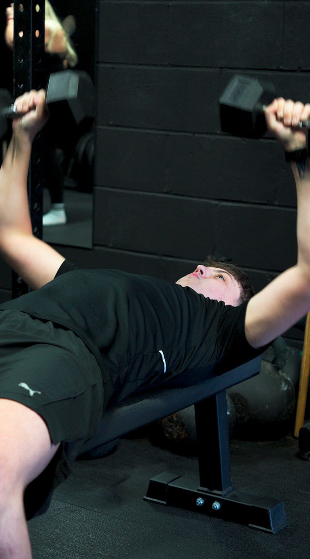A member doing a dumbbell bench press