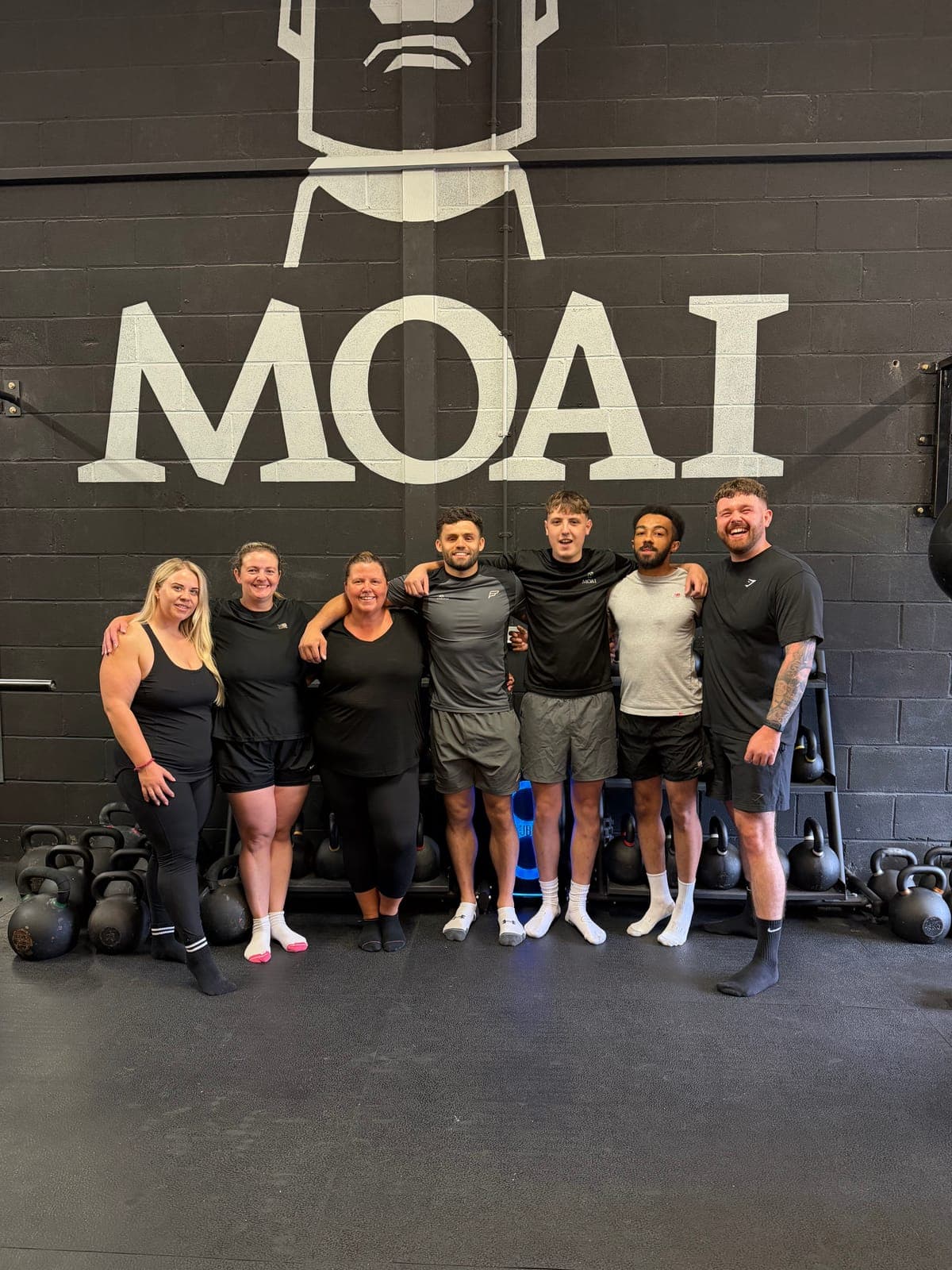Moai members and coaches in front of the Moai wall